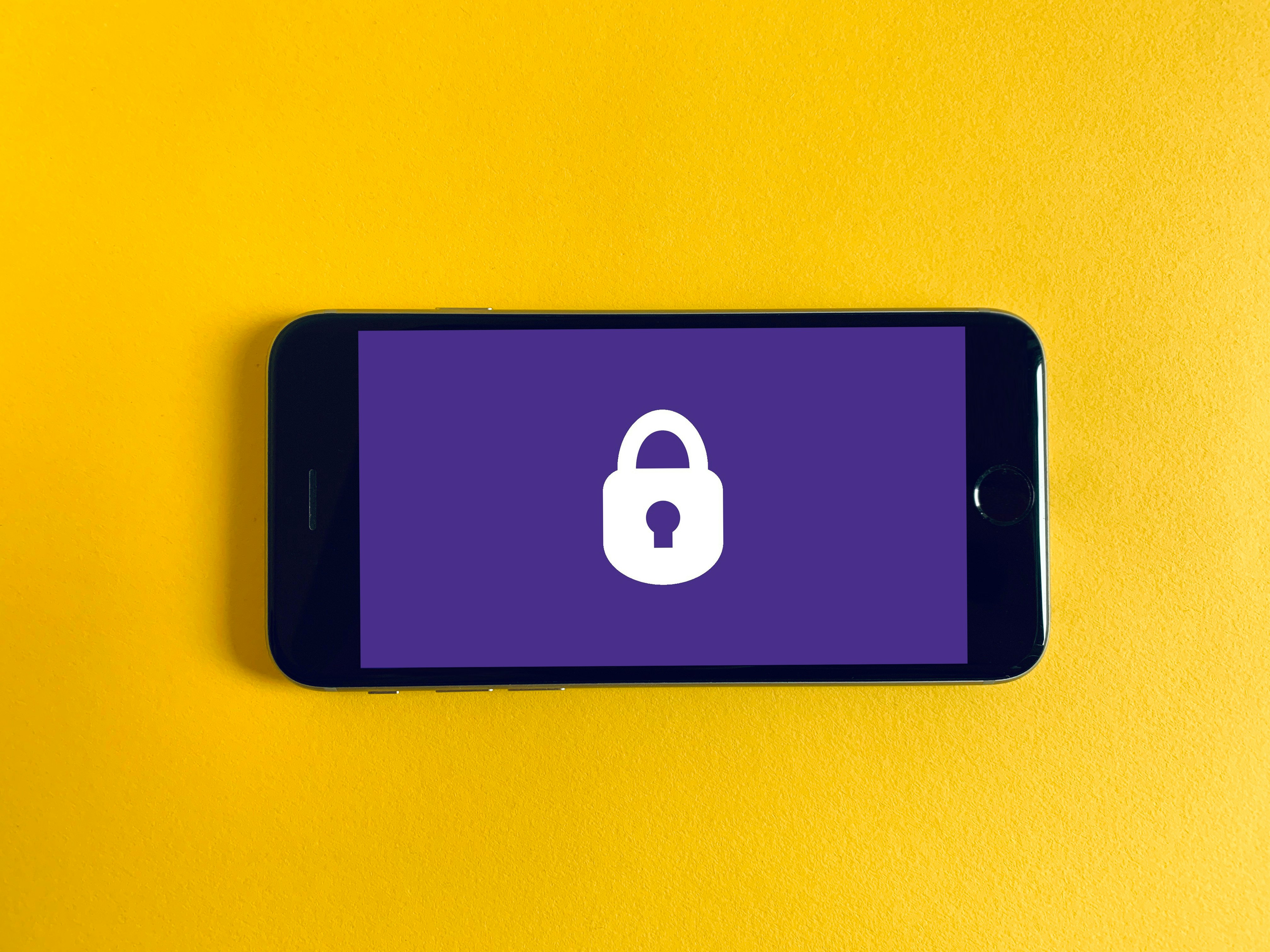 A device on a yellow background. The device is landscape orientation and shows a purple screen with a padlock